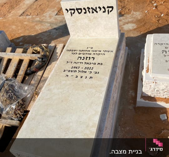 מצבה עם כיתוב בעברית על רקע אדמה